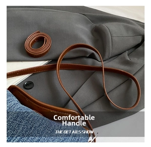 Close-up of brown leather strap and blue denim fabric with black button details