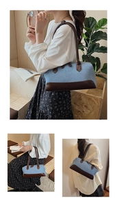 Detail of light blue textured fabric shoulder bag with dark brown leather trim and handles