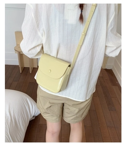 Détail du sac selle en cuir verni jaune pâle avec bandoulière réglable et rabat