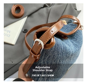 Detail view of denim shoulder bag featuring brown leather strap and silver metal buckles