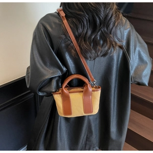 Detail of canvas and brown leather crossbody bag styled with a sleek black leather jacket