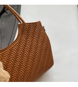 Détail du sac panier tressé marron foncé montrant la texture cuir et le charm en peluche