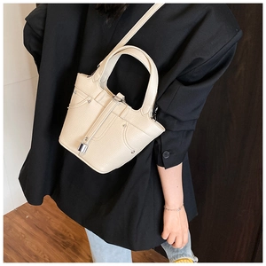 Détail du sac seau beige à motif litchi avec serrure avant et bandoulière