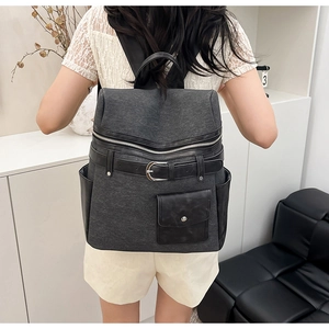 Detail view of the dark gray fabric backpack with leather trims on a model