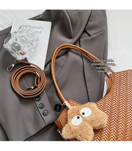 Détail du sac tressé marron avec charm monstre sur une veste de tailleur grise