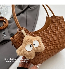 Détail d'un sac cabas tressé marron avec une breloque étoile en peluche et bandoulière fine