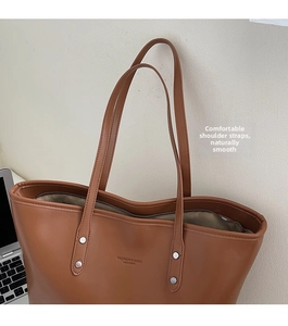 Close-up of brown leather tote bag showing comfortable shoulder straps and metal buckle