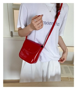 Détail d'un sacoche en cuir verni rouge avec finition brillante et bouton pression