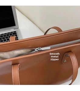 Close-up of premium silver metal zipper and smooth stitching on a brown tote bag