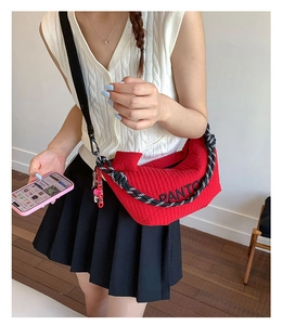 Red quilted crescent shoulder bag featuring black letter print and knot rope strap
