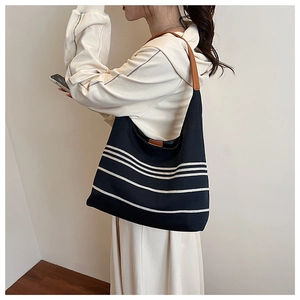 Detail of waterproof nylon tote with black and white stripes and brown leather straps
