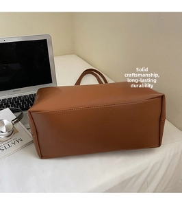 Detailed side view of brown leather tote bag with sturdy stitching and dual handles