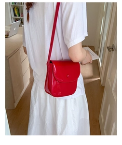 Sacoche en cuir verni rouge portée par un mannequin dans un cadre de vie intérieur