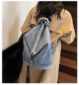 Détail d'un sac à dos en jean délavé avec fermeture éclair verticale et bretelles réglables