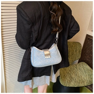 Detail showing light blue rhinestone underarm bag with silver magnetic clasp on a model