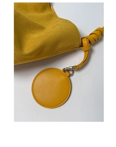 Detailed macro view of yellow suede bucket bag with leather knot and silver metal clasp