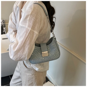 Detail of light blue rhinestone denim shoulder bag with silver buckle on white linen shirt