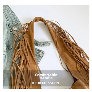 Detailed macro view of brown suede tote bag featuring bohemian long fringe tassels
