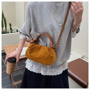 Detail van gele geplooide crossbodytas met knoophengsel en verstelbare riem gedragen door model