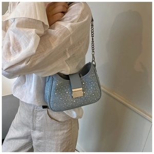 Detail of light blue denim handbag featuring sparkling rhinestones and silver chain strap