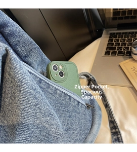 Vue détaillée d'un sac en denim avec poche zippée avant contenant un smartphone