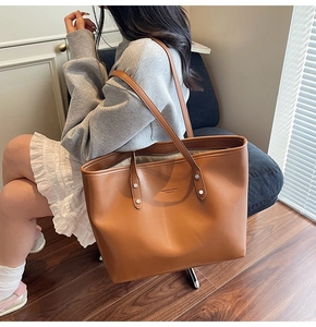 Brown leather tote bag featuring silver studs and fashion brand logo text detail