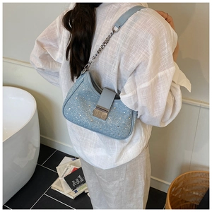 Detail of light blue denim shoulder bag featuring silver rhinestones and chain strap