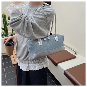 Détail du tissu bleu texturé et de la bordure argentée de ce sac à bandoulière chic