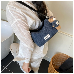 Detail of blue denim bucket bag with teddy bear charm and silver metal hardware