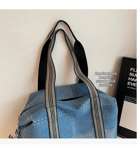 Detail of denim tote bag with reinforced striped handles and white quilted stitching