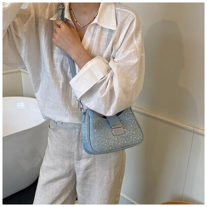 Close-up of light blue denim rhinestone bag with silver buckle and leather strap