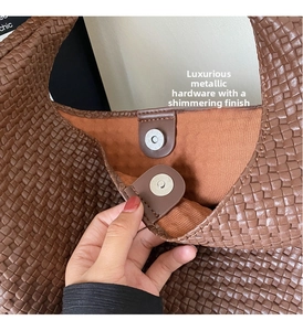 Detail of silver magnetic closure and woven leather texture on a caramel brown tote