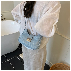Detail of light blue denim crescent bag with sparkling rhinestones and silver buckle