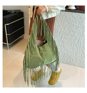 Detail of green suede tote bag with long fringe tassels in bohemian style