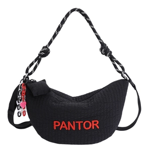 Close-up of black quilted crescent bag with red embroidery and woven rope handle