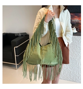 Macro view of green suede fringe tote bag showing detailed texture and bohemian tassels