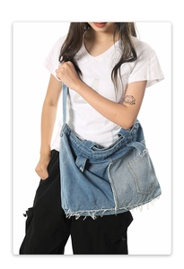 Detail view of denim patchwork tote bag with frayed edges and retro street style
