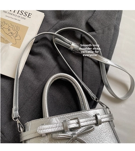 Detail of silver metallic bucket bag with ribbon bow and textured finish on a blazer