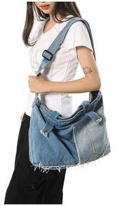 Detail of blue denim patchwork tote bag with frayed edges and adjustable canvas strap