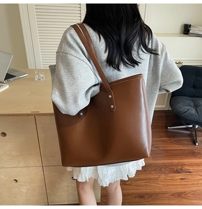 Detailed view of a brown leather tote bag with silver rivets in a modern office setting