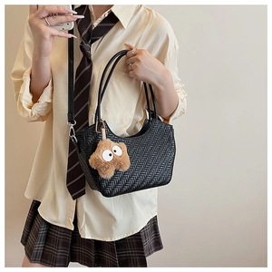 Détail du sac cabas tressé noir avec un charme étoile en peluche sur le modèle