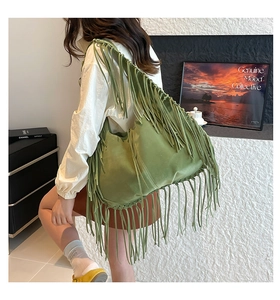 Detailed view of bohemian green suede tote bag with long fringes worn on shoulder