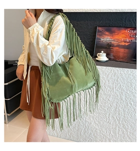 Green suede tote bag featuring long fringes shown on model in a minimalist setting