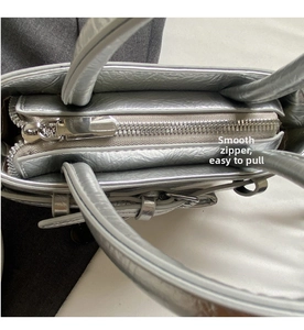 Close-up of smooth silver metal zipper and wrinkled leather detail on bowling bag