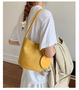 Yellow soft leather bucket bag worn by model, minimalist shoulder bag style