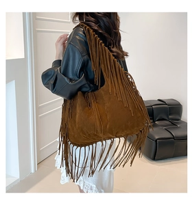 Detail of dark brown suede shoulder bag with dense tassels and bohemian fringe texture