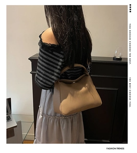 Détail du sac à bandoulière en cuir camel avec texture souple et finitions argentées