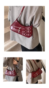 Makro-Detail der weinroten Lackleder-Achseltasche mit Punk-Schnallen und Metallreißverschlüssen