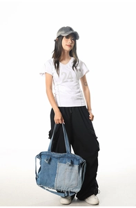 Detailed view of a large patchwork denim tote bag with raw fringe on stylish casual outfit