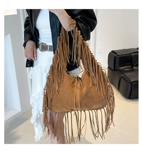 Brown suede shoulder bag with long fringes shown on a model in a modern interior
